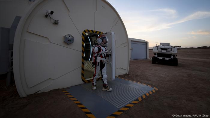 A woman wearing a spacesuit walking out of Mars Base 1, a C-Space Project, in the Gobi Desert