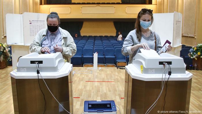 Zwei Frauen mit Mundschutz an Wahlautomaten in einem Theater in Moskau
