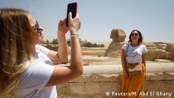 Une femme pose pour une photo devant le Sphinx des Grandes Pyramides de Gizeh