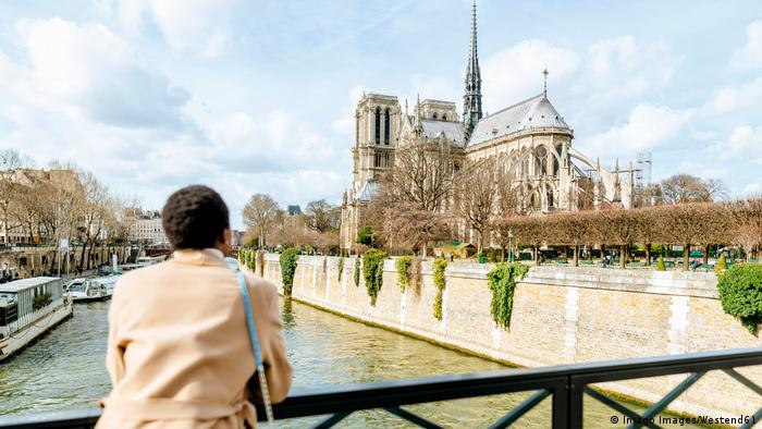 Woman looking at Notre Dame de Paris from bridge against sky, Paris, France model released