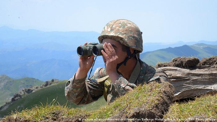 Армянский солдат смотрит в бинокль в сторону границы с Азербайджаном