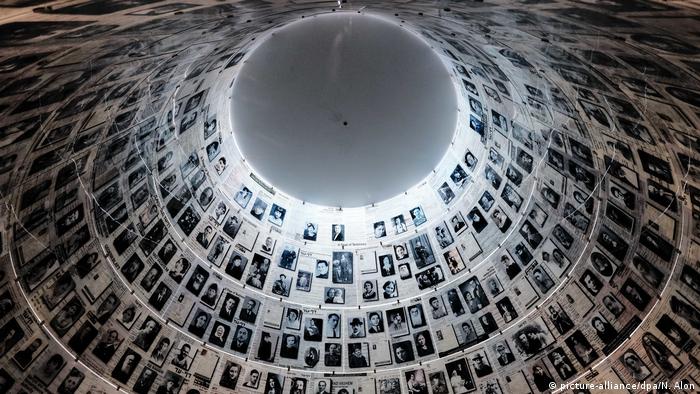Blick von unten in eine Art runde Kuppel, an deren Wänden schwarz-weiße Fotos mit Gesichtern von Menschen darauf hängen
