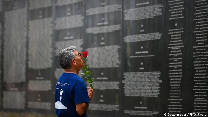 Foto de un familiar víctimas desaparecidas de la guerra civil frente al monumento que les conmemora en San Salvador
