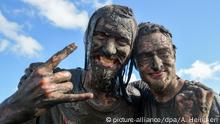 Mit Schlamm überzogene Metal-Fans feiern am 05.08.2016 in Wacken (Schleswig-Holstein) auf dem Festivalgelände des Wacken Open Air. Das nach Veranstalterangaben größte Heavy-Metal-Festival der Welt wird von 75000 Fans besucht. Foto: Axel Heimken/dpa +++(c) dpa - Bildfunk+++ | Verwendung weltweit