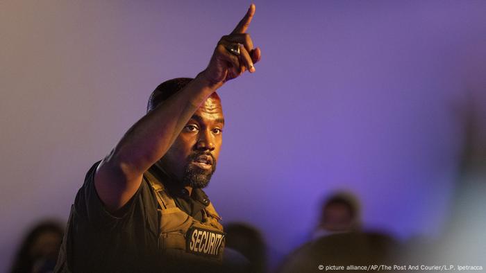 Rapper Kanye West holds his arm aloft while pointing a finger