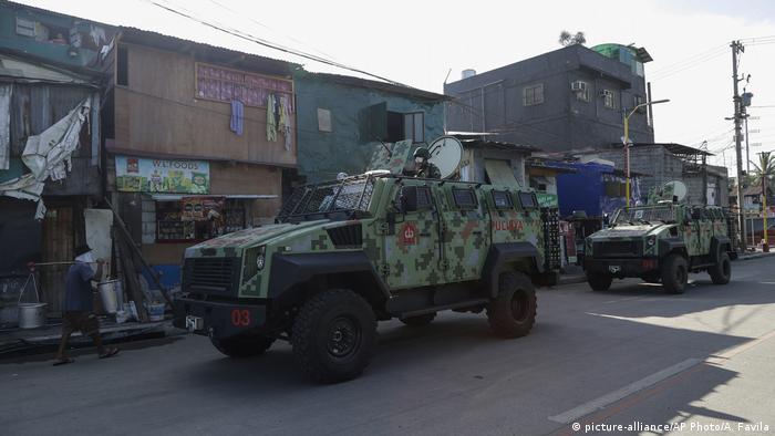 Police armored personnel carriers pass by homes during the start of a lockdown in the city of Navotas on July 16