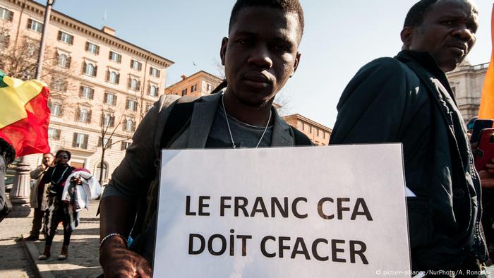 A demonstrator holds a placard protesting CFA currency.