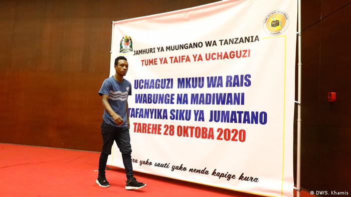 A man walks past a banner with graphics on Tanzania's 2020 election