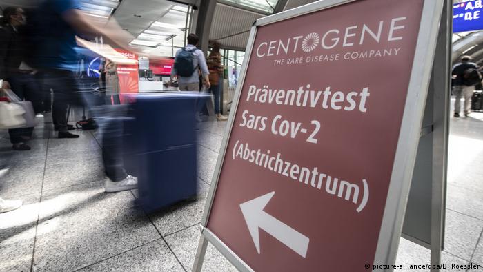  Passagiere gehen am Flughafen Frankfurt an einem Wegweiser zum Corona-Testzentrum vorbei 