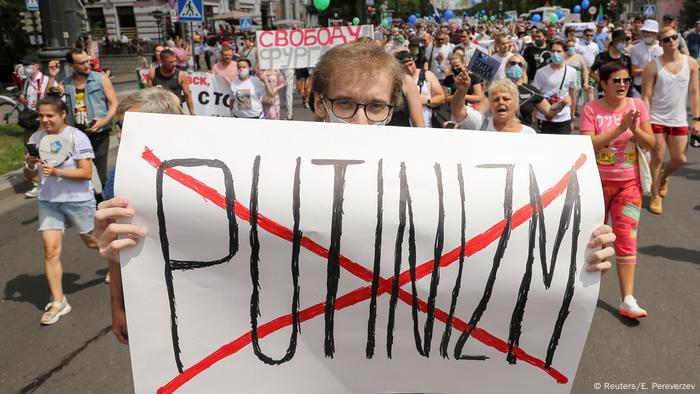 Demonstranten mit einem Plakat, auf dem durchgestrichen Putinizm steht