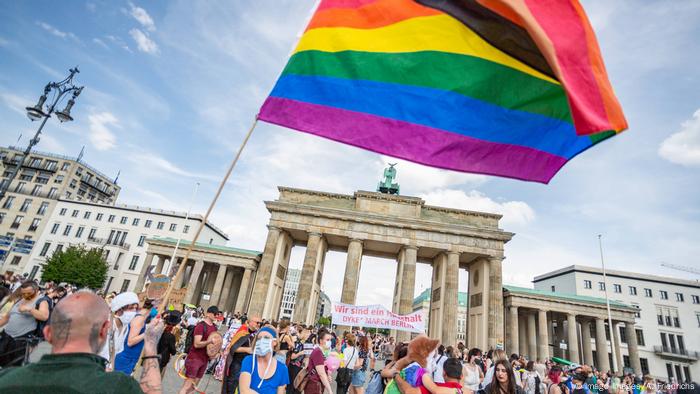 Demonstrant schwenkt Regenbogenfahne vor dem Brandenburger Tor