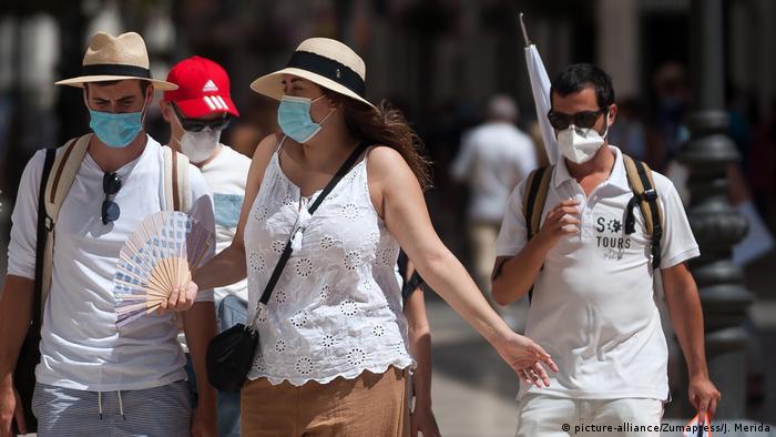 Tourists wearing face masks walk along the Marques de Larios street in Malaga