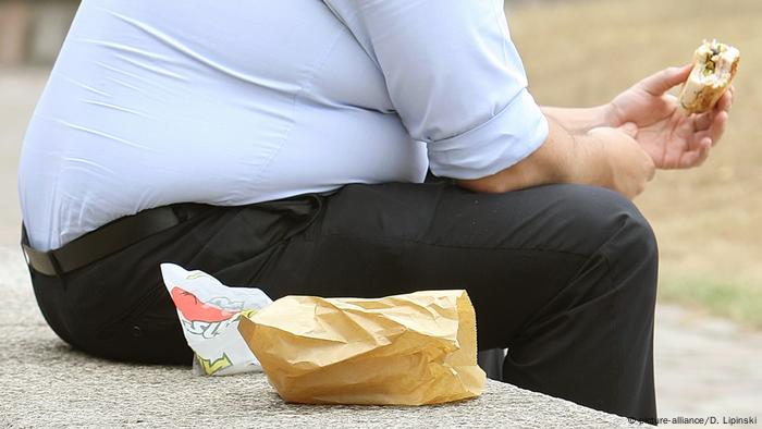 Overweight man eating a hamburger