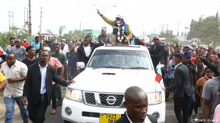 Tundu Lissu waves to a crowd from the back of an open car in Dar es Salaam