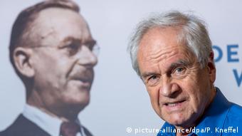 Frido Mann stands in front of a poster with a portrait of his grandfather Thomas Mann in the Munich Literaturhaus

