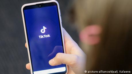the Chinese platform Tik Tok viewed on a mobile phone with a right thumb on the screen