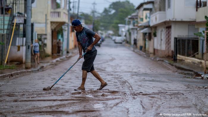 In this July 2020 file photo, a man sweeps mud from a street after Tropical Storm Isaias affected the area in Mayaguez, Puerto Rico