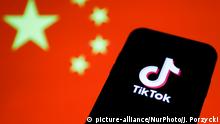 TikTok logo is seen displayed on a phone screen with Chinese flag in the background in this illustration photo taken on August 2, 2020. President of the USA Donald Trump said that Chinese app TikTok will be banned in the United States. (Photo Illustration by Jakub Porzycki/NurPhoto) | Keine Weitergabe an Wiederverkäufer.