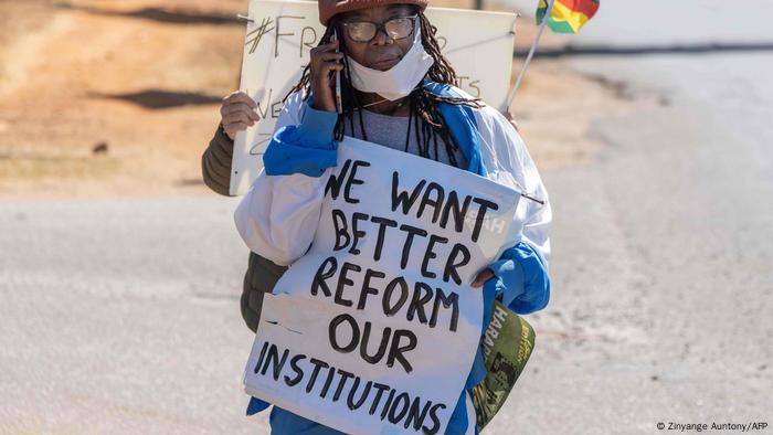 Tsitsi Dangarembga holding a placard that reads: We want better, reform our institutions.