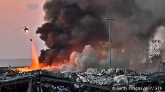 Flammen über zerstören Gebäuden, am Himmel ein Lösch-Hubschrauber