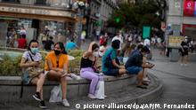 28.07.2020, Spanien, Madrid: Menschen mit Mundschutzmasken sitzen auf einer Straßenbank. Als letzte Region auf dem spanischen Festland hat nun auch die Hauptstadt Madrid eine umfassende Maskenpflicht zur Verhinderung von Corona-Infektionen angekündigt. Foto: Manu Fernandez/AP/dpa +++ dpa-Bildfunk +++
