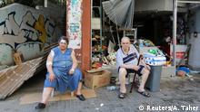 A woman, who was injured in Tuesday's blast, sits next to her husband outside their damaged grocery in Beirut, Lebanon August 5, 2020. REUTERS/Aziz Taher