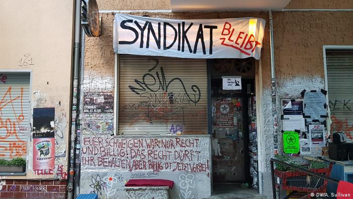 Picture of the outside of the Syndikat bar, showing a lelfmade poster with the slogan Syndicat Stays 