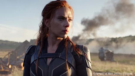 Schauspielerin Scarlett Johansson als die Schwarze Witwe in einem futuristischen Kostüm vor einem Hintergrund, in dem Qualm aufsteigt.