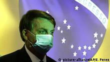 Brazil's President Jair Bolsonaro wears a protective face mask at the start of a ceremony where his nation's flag is projected in Brasilia, Brazil, Wednesday, Aug. 5, 2020. The Brazilian Supreme Court ordered Bolsonaro's administration Wednesday to adopt measures to shield Indigenous peoples from the new coronavirus, in a vote that came hours after a prominent Indigenous leader died from COVID-19. (AP Photo/Eraldo Peres) |