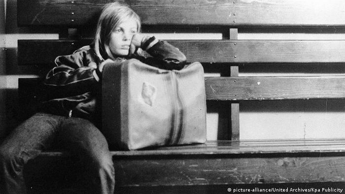 Filmszene aus Alice in den Städten von Wim Wenders: Ein junges Mädchen sitzt gelangweilt mit einem großen Koffer auf einer Bank (Bild: picture-alliance/United Archives/Kpa Publicity)
