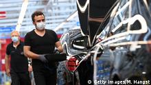 SINDELFINGEN, GERMANY - APRIL 30: Workers wear protective face masks as they assemble cars at the Mercedes-Benz factory following the resumption of automobile production this week during the novel coronavirus crisis on April 29, 2020 in Sindelfingen, Germany. Auto production at car manufacturers' factories across Germany had been shut down since March due both to lockdown measures meant to stem the spread of the virus as well as disruptions in supply chains. Many factories have reopened this week as Germany takes careful steps to ease restrictions in a bid to revive economic activity. (Photo by Matthias Hangst/Getty Images)