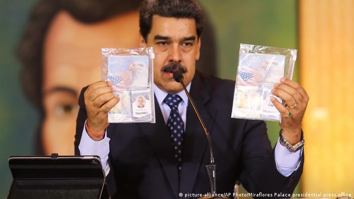 Nciolas Maduro holds up the passports of the two imprisoned men