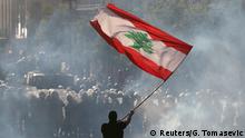 A demonstrator waves the Lebanese flag in front of riot police during a protest in Beirut, Lebanon, August 8, 2020. REUTERS/Goran Tomasevic TPX IMAGES OF THE DAY