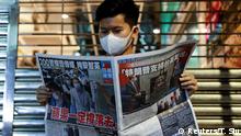 A supporter of Apple Daily newspaper, reads a copy of Apple Daily newspaper to support media mogul Jimmy Lai Chee-ying, founder of Apple Daily after he was arrested by the national security unit, in Hong Kong, China August 11, 2020. REUTERS/Tyrone Siu
