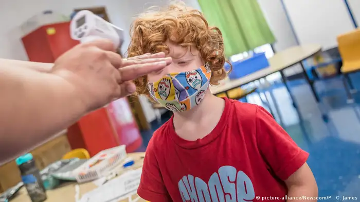 A young boy in a mask has his temperature checked at school (picture-alliance/Newscom/P. C. James)
