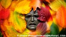 schmerzverzerrte Maske im Herbstlaub, Symbolfoto Herbstdepression, Deutschland | masks among autum leaves, autum blues, Germany | Verwendung weltweit