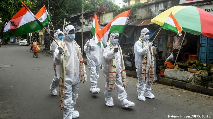 Индийские медработники в защитных костюмах держат флаги Индии на праздновании дня независимости 15 августа