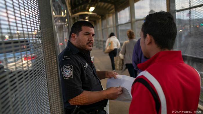 Un policía controlando a un hombre en la frontera entre Estados Unidos y México.