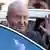 Spain's former king Juan Carlos I waving as he enters a car