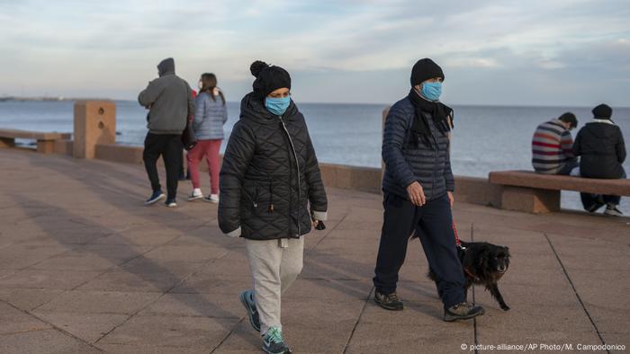 People walking on the promenade in Montevideo wearing masks