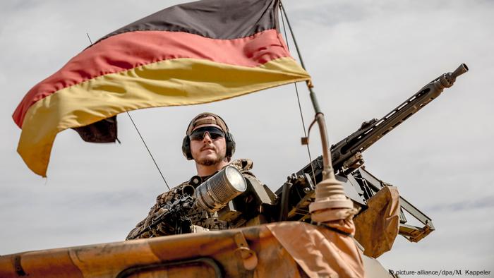 A German soldier on top of a military vehicle.