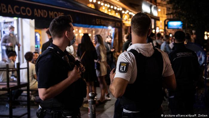 Two policemen observing young people on an evening street