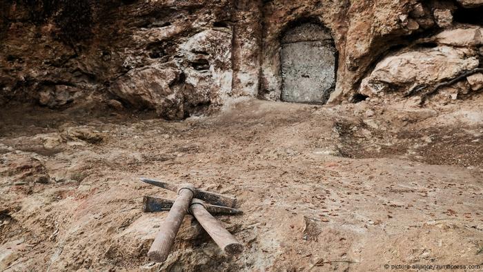 Zwei Spitzhacken liegen vor einer Höhle, die mit eienr Tür verschlossen ist (picture-alliance/zumapress.com)