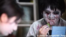 This picture taken on June 15, 2020 shows actor Kenta Iwana (R), 25, putting on zombie makeup before a demonstration of a drive-in haunted house at a garage in Tokyo. - A car horn beeps and the horror begins: a bloody murder and rampaging zombies. But this drive-in haunted house in Japan protects against the most terrifying enemy of all -- coronavirus. Inside a car, guests can scream as loudly as they like, with no mask required, as hideous creatures daubed in blood swarm towards them. (Photo by Philip FONG / AFP) / TO GO WITH AFP STORY JAPAN-ENTERTAINMENT-HEALTH-VIRUS-HORROR,FOCUS BY HARUMI OZAWA (Photo by PHILIP FONG/AFP via Getty Images)