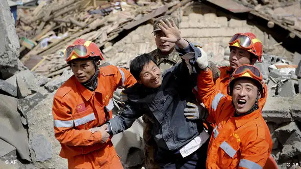 Ein Überlebender umringt von seinen Rettern winkt, nachdem er aus einem zerstörten Gebäude geborgen werden konnte (Foto: AP)