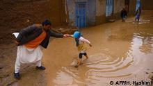 ARCHIV 2019 *** In this photograph taken on March 29, 2019, an Afghan man helps a girl as she wades along a street affected by flash floods in Herat province. - Flash floods caused by heavy rains have killed at least 35 people in Afghanistan, washing away houses and cutting off access to remote villages across parts of the country, officials said on March 30. (Photo by HOSHANG HASHIMI / AFP)