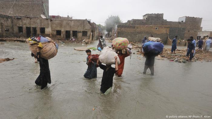 Residents wade through a flooded area in a village near Karachi after heavy monsoon rains lash the area