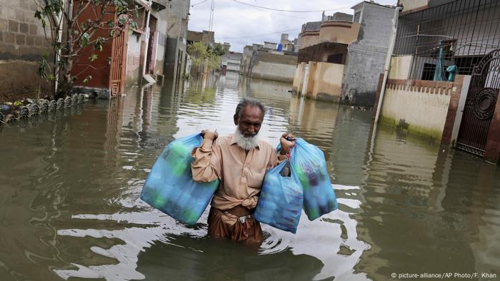 A man wades through a flooded street after heavy rains in Karachi, Pakistan