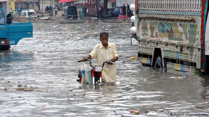 A man pushes his motorcycle through floodwater in the southern Pakistani port city of Karachi on Aug. 26, 2020