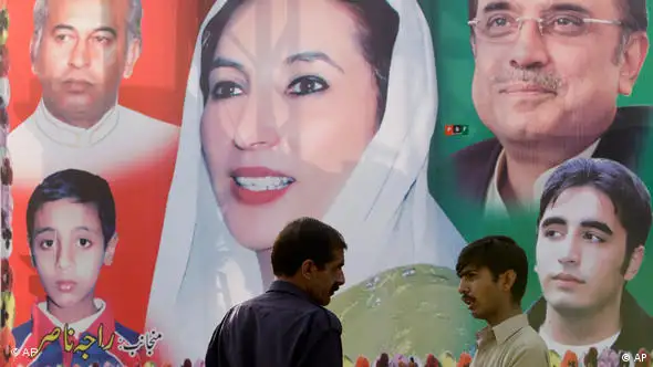 Zwei Männer stehen vor einer Plakatwand, in deren Mitte ein Bild von Benazir Bhutto zu sehen ist (Foto: AP)
